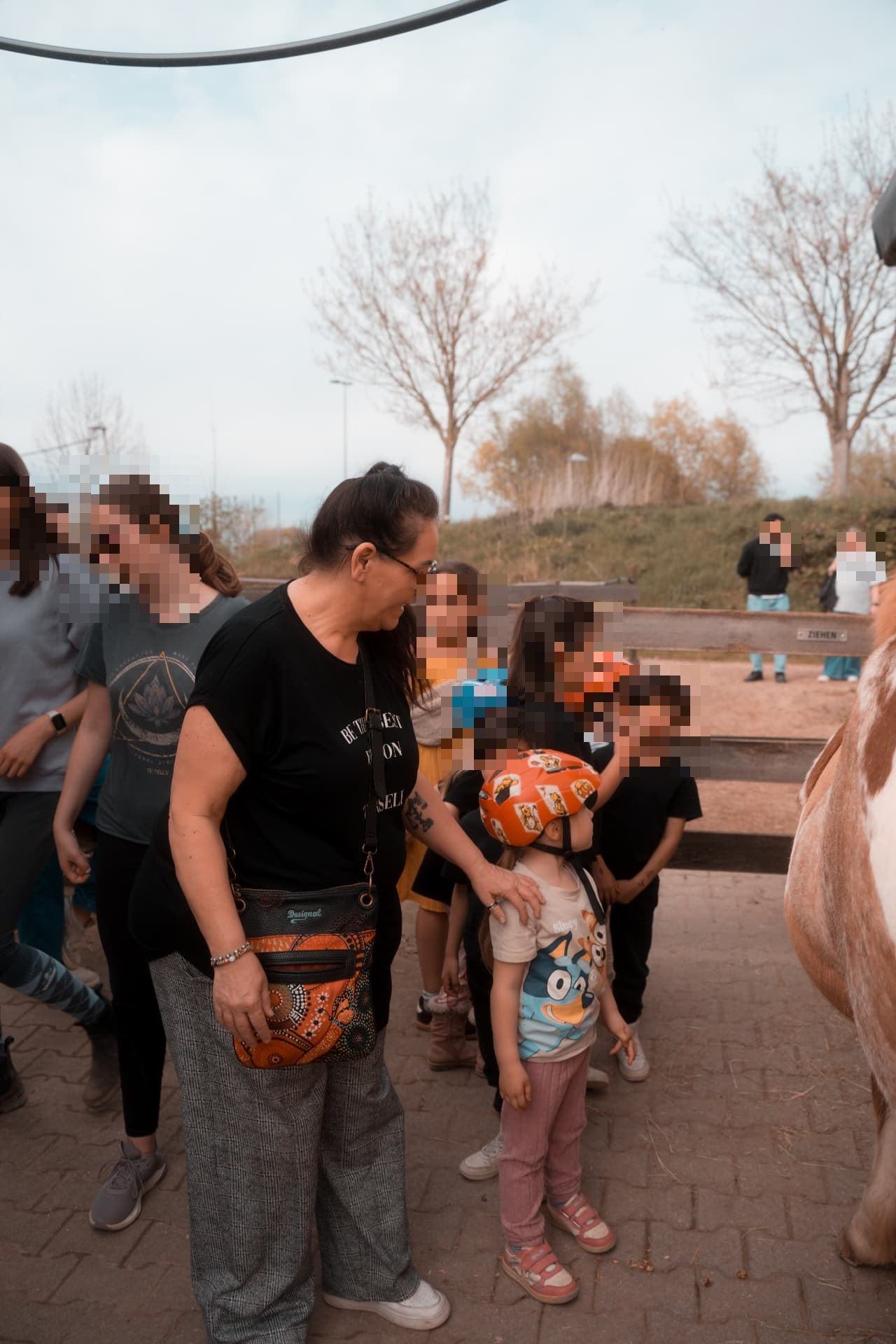 Kinder und Betreuerinnen stehen an einem Ponyplatz, Gesichter unkenntlich gemacht